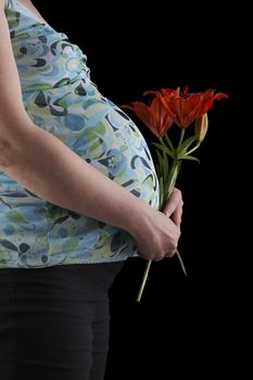 A pregnant young woman on a black background.