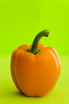 Single orange pepper over the green background