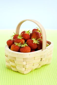 Basket filled with strawberries over lime taple top.