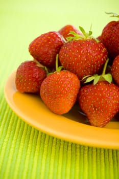 Strawberries piled on the yellow plate over lime background