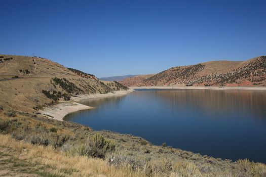 Lovely lake and blue sky contrasts with brown Utah hills.