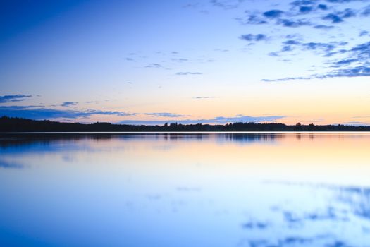 summer sunset on the lake with clouds reflection