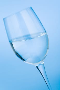 Wine glass filled with water over blue background