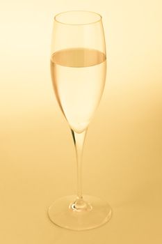 Golden sparkling wine glass over a yellow background