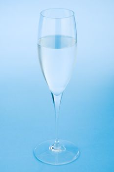 Sparkling wine glass filled with water over a blue background