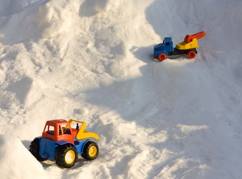 Coloful toy cars left in the snow.