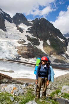 Traveller woman with ice-axe standing on flowering meadow