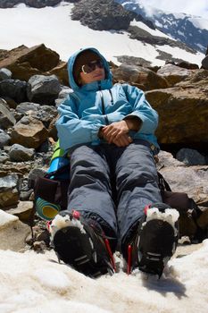 Girl in crampon relaxing on snow in mountains