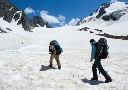 Couple of hikers climb to pass in high mountains