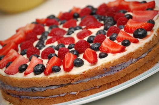 Fruit cake dessert closeup. Garnished with strawberries, blackberries, raspberries