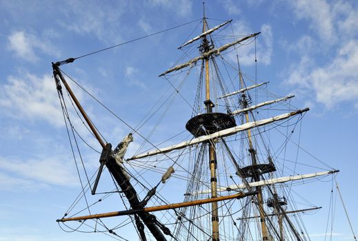 Landscape view of tall ship rigging against blue cloudy sky