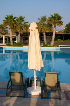 sunshade and couch near of swimming pool in tropical resort