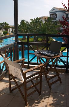 table with laptop and cup of coffee on the balcony in resort