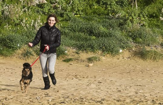 Woman running with her pet dog at a beach