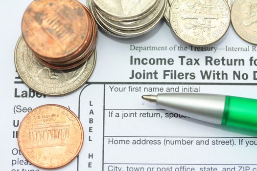 Some American coins and a green pen on an IRS income tax return form