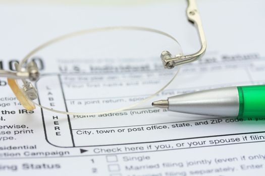 A pair of glasses and a green pen on an income tax return form