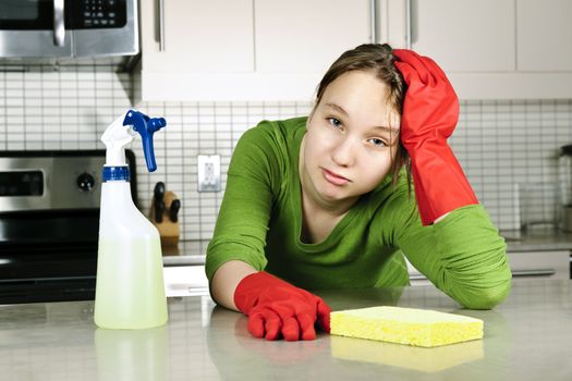 Tired girl doing kitchen cleaning chores with rubber gloves