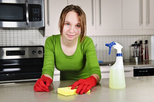 Young woman doing kitchen cleaning chores with rubber gloves