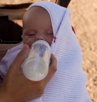 Mother feeding her child with bottle of breastmilk