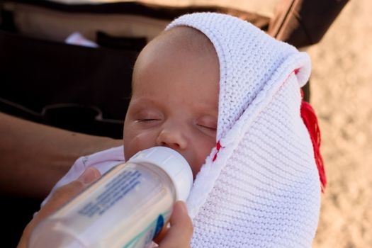 Mother feeding her child with bottle of breastmilk