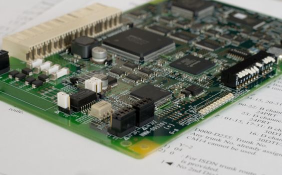 Printed circuit board over technical documentation (close-up photo)