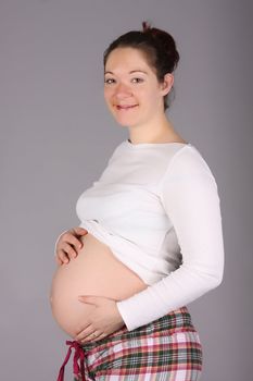 pregnant woman holding belly on grey background