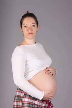 pregnant woman holding belly on grey background