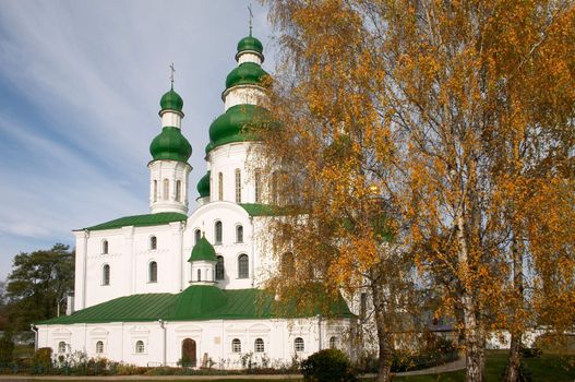 old church and golden fall tree near of it