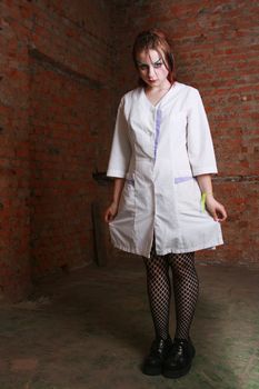 The strange girl in a hospital dressing gown costs in a cellar