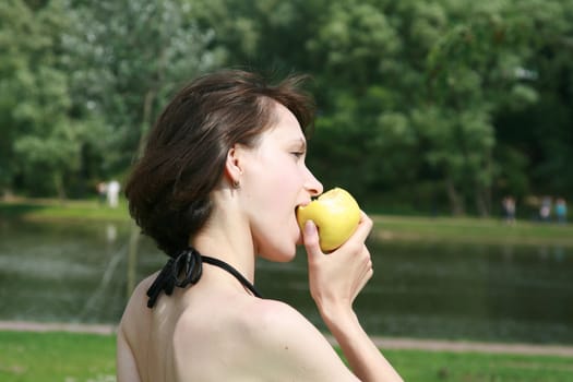 The young woman eats an apple in a sunny day