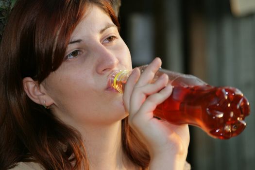 The girl drinks a water from a plastic bottle