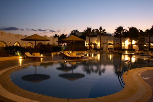 swimming pool with evening illumination in tropical resort