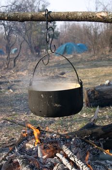 Kettle with food above the fire in the camping