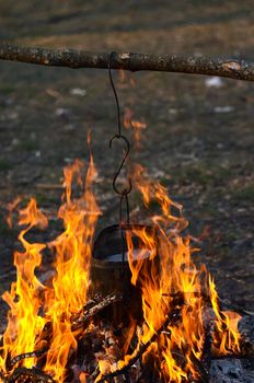 kettle with water hanging  in the fire in camping