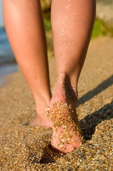 Girl's legs on sand beach at seaside