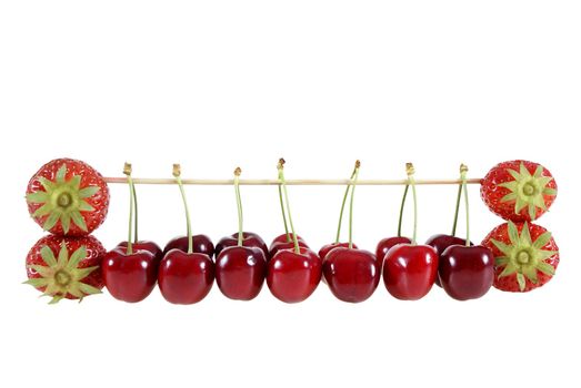 strawberries and cherries suspended on a stick isolated on the white background