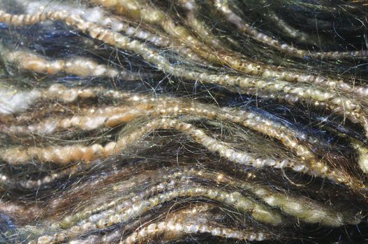 close-up (macro) of blue and yellow mohair yarn wrapped in gold strands, forming wavy lines