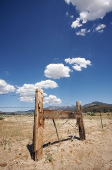 Puffy Storm Clouds Forming Over Field and Aged Fence on a blue sky.