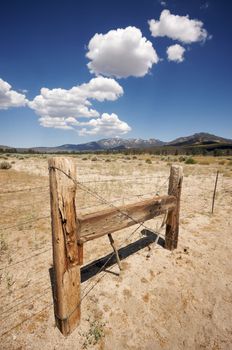 Puffy Storm Clouds Forming Over Field and Aged Fence on a blue sky.