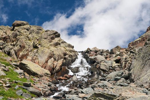 fresh waters are flowing with a small cascade under a blue sky. Photo taken with polarized filter