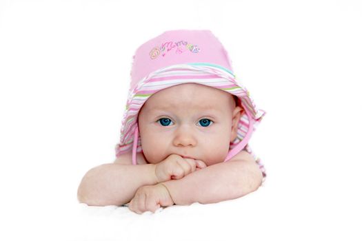 Baby with pink hat and blue eyes looking into the camera