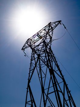 High voltage electricity pylon with bright summer sun