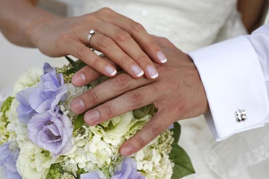 Hand of the groom and the bride with wedding bouquet