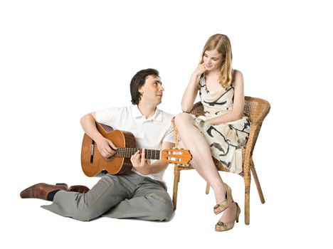 A blond girl and a man playing guitar for her