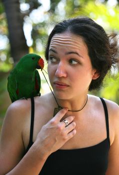 The girl with a green parrot on a shoulder. Bali. Indonesia