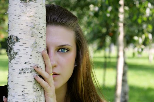 The blue-eyed girl looks out because of a tree