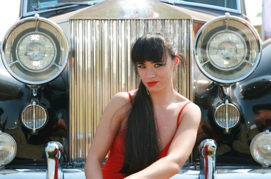 The girl poses in front of the beautiful car