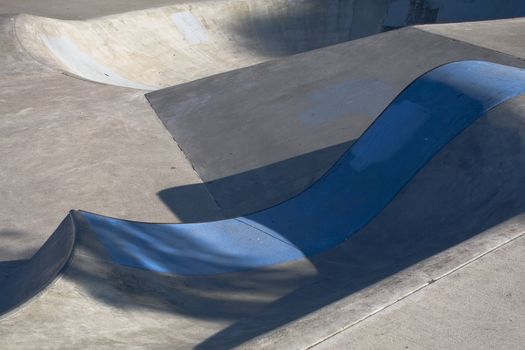 A skateboard park bowl with a blue painted concrete lip.