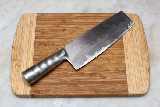 Closeup image of chinese kitchen knife on cutting board.