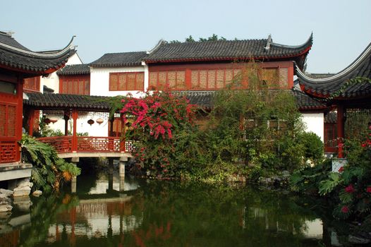 Chinese, traditional, wooden houses with simple garden, pond and small bridge.